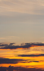 Sunset sky, lines of dark clouds, orange haze. Vertical beautiful natural background.