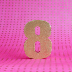 Golden volumetric number 8 on a bright pink polka dot background. copy space..