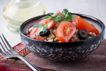 Salad of tuna fish with tomatoes in a black salad bowl