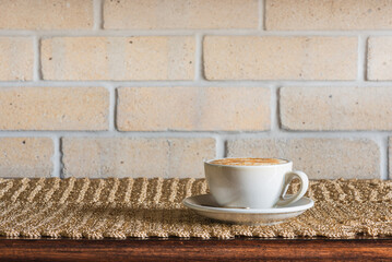 Coffee Cappuccino on Table with Brick Wall Background