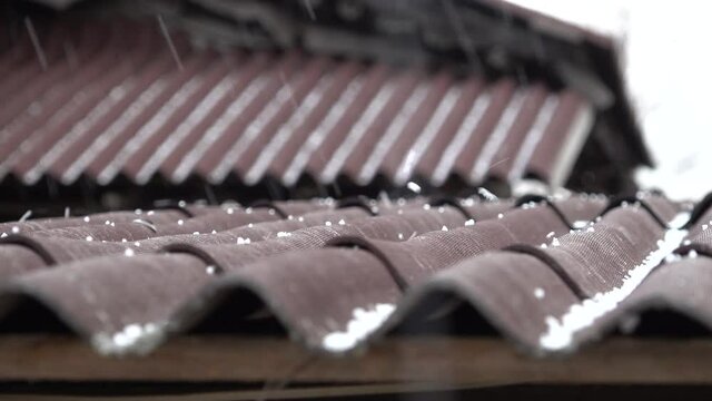 it's hailing hail falls and rolls down on the roof burgundy brown roof
