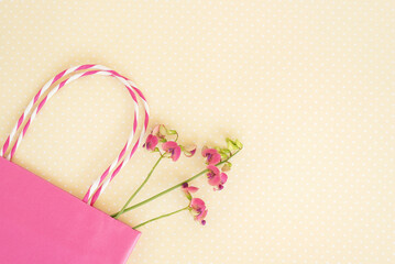 Purple wild flower, pink shopping bag. Concept of seasonal summer discounts.