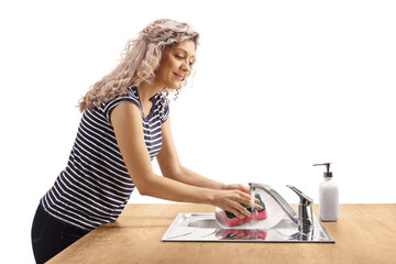 Profile shot of a young woman washing a plate with a sponge