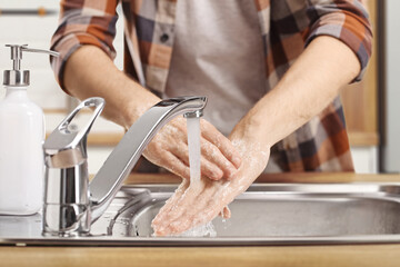 Shot of male hands washing in a kitchen sink