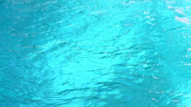 Beautiful sparkling shiny texture of blurry blue water with sun reflected on surface of water
