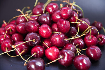 Red fresh cherries on a black background. Drop of water. Close up. The concept of freshness.