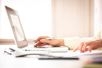 Close-up shot of businesswoman's hand while typing on keyboard and using calculator in the office