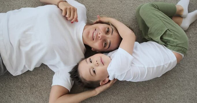 Loving mother and son having fun lying on the floor at home