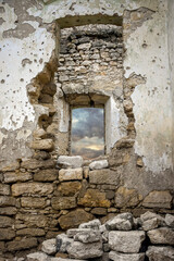 Dilapidated stone walls of medieval desolate building. Masonry, rooms with arched vaults. Stormy sky is visible through window. Selective focus.