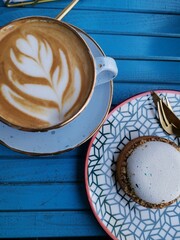 Mug of coffee with dessert on a wooden blue background.