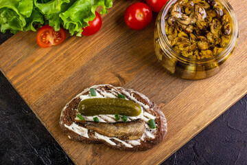 Sandwich with sprots and cucumber, on a board with tomatoes and salad