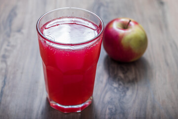 Glass of apple juice and ripe apples on a kitchen table