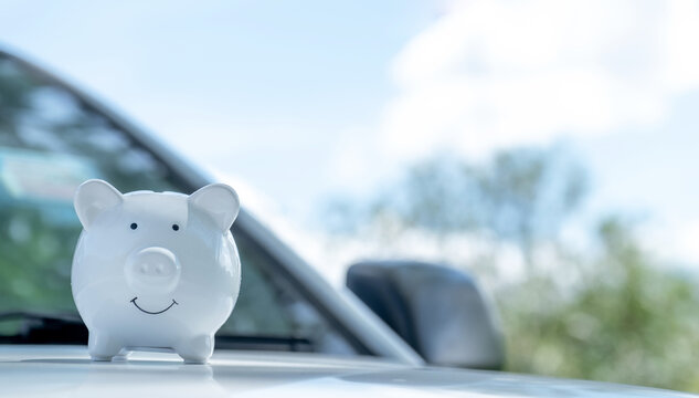 White piggy bank on the car, Money-saving concept for insurance, or traveling during retirement