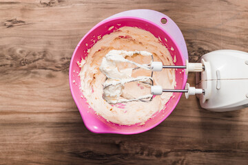 whipped butter, bowl with butter and whisk for beating on a wooden table, mixer