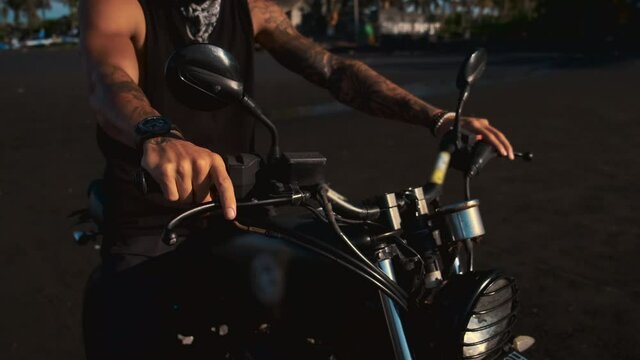 biker on motorcycle on sandy beach, closeup