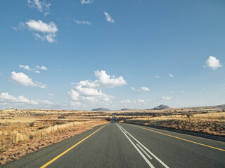 Deserted landscape with long winding road and dramatic clouds and sky.