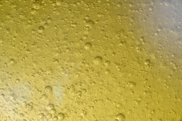 Close-up macro fullscreen with shallow depth of field of bubbles inside a yellow liquid. Graphic design.