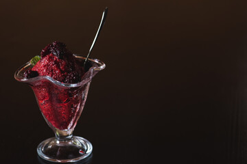 Dessert, frozen yogurt or ice cream in a transparent container on a dark gray background. Garnished with fresh mint. Summer desserts concept. Copy the space.