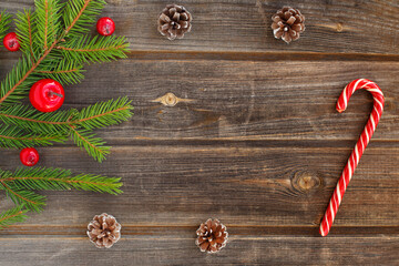 New year flat lay: Christmas green spruce branch of new year tree with red sugar snow apples, candy cane, cones on a rustic wooden background