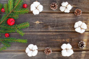 New year flat lay: Christmas green spruce branch of new year tree with red apples, candy cane, cotton flowers, cones on a rustic wooden background