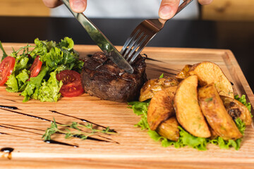 Juicy thick juicy portions of roasted steak fillet with tomatoes and roasted vegetables on an old wooden board 