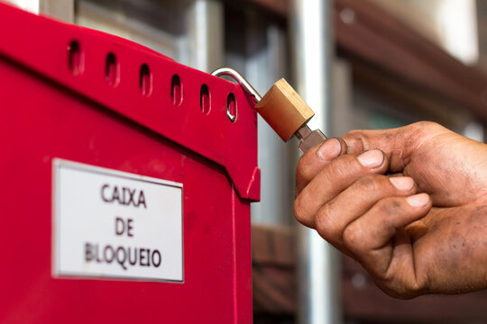 Man holding a key oppening a padock in a safety red box with dirty hands
