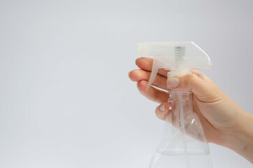Female hand holding a hand sanitizer near the spray bottle on a white background