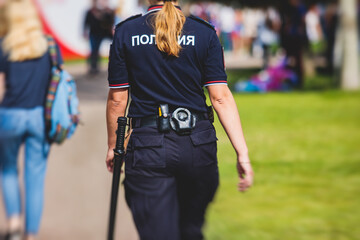 Russian female police squad formation back view with "Police" emblem on uniform maintain public order after football game with football fans crowd in the background