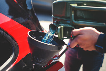 Process of refueling the sportcar tank with gasoline from canister during test-drive racing...