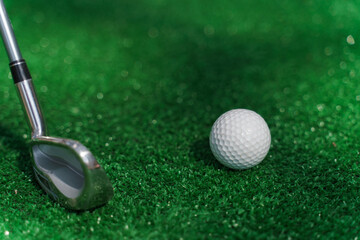 Close-up niblick and white ball for golf on the green grass. Empty right side for text of advert for golf clubs. Playing in golf