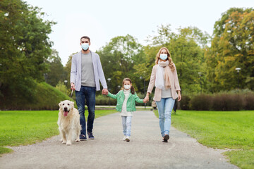 family, pandemic and health concept - mother, father and little daughter wearing medical face mask for protection from virus disease walking in summer park with labrador retriever dog