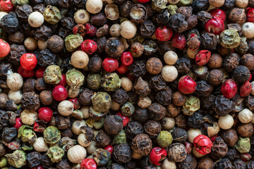 Fullscreen macro closeup with shallow depth of field of unmilled red, green, white and black peppercorns