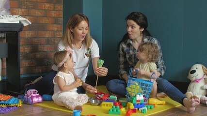 Little girls and they mams are playing with Colorful plastic bricks