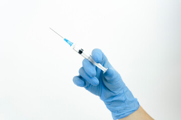 Doctor hand in a blue glove with a syringe on a white background.