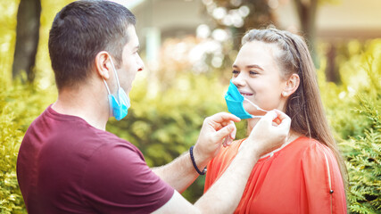 Happy couple removing protective face mask after coronavirus lockdown reopening