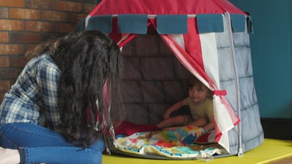 Little cute girl with blond hair playing in toy house