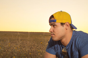 Young latin man posing from front in a blue shirt black glasses and a tricolor cap