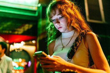 Ginger woman is using her smartphone on the street.