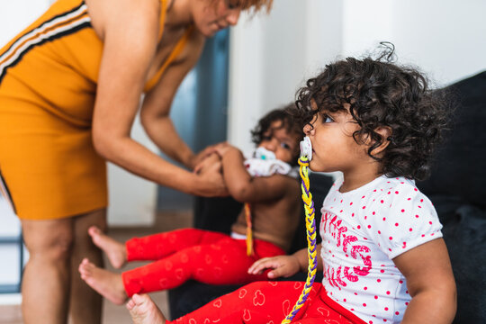 Mother of one years old twin girls is dressing one of them