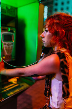 close up of a young woman holding a public phone at night