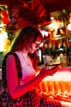 side view of a woman texting to someone else at the bar