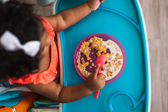 Top view of a baby girl eating cereals.