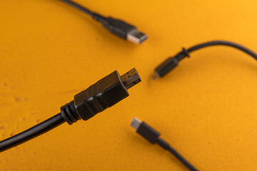 computer wire hdmi against the background of different wires from the computer and phone are on the orange table