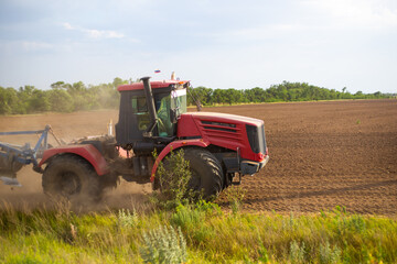 Fototapeta premium tractor plows the land for sowing, with a plow on a sunny day, agriculture