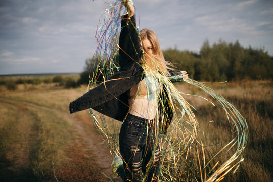 Appealing woman dancing with bright tinsel in field