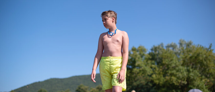 Young blond teenage boy is walking on a beach - Powered by Adobe
