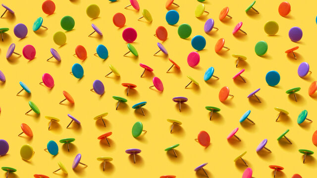 Stationery pins pattern different colours on an yellow.