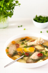Chicken soup with fresh vegetables, chicken wings broth and young potatoes with onions and carrots, chopped green onions and parsley