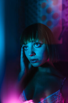 portrait beautiful girl behind glass with red blue lighting