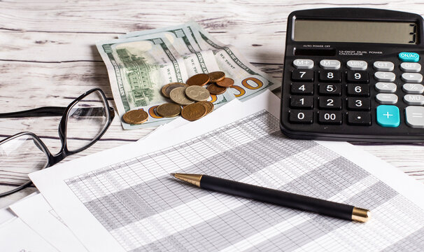 A calculator, money, glasses and pen lie on the desktop. Business concept